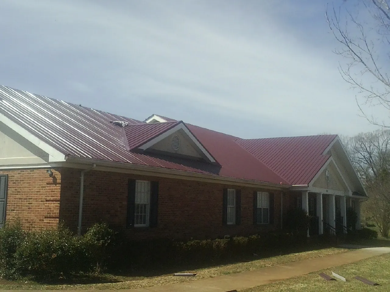 Red metal roof with gabled entries on a long brick building in Sanford