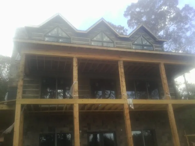 Dormers and porch framing on a large log home under construction — Roof Coating work by our crew in Sanford
