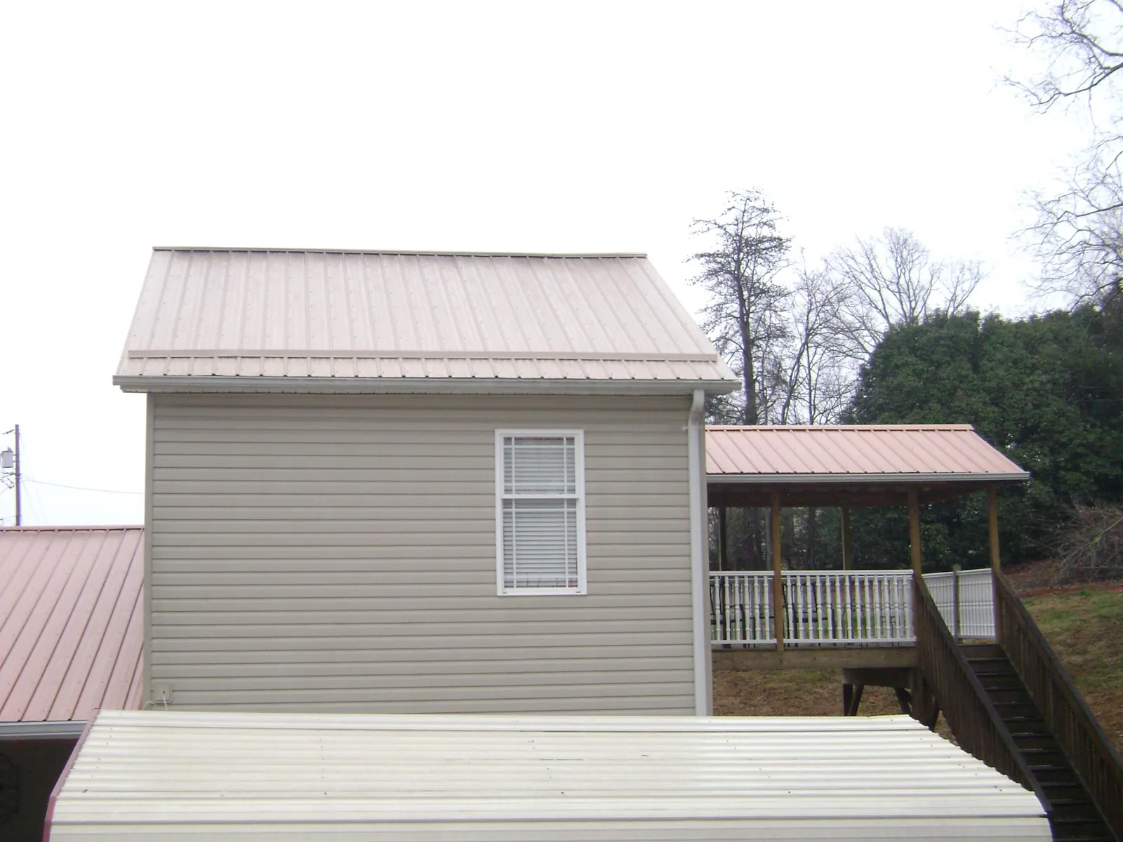 Tan metal roofs on a two story addition and attached porch, from a Roof Replacement job in Sanford
